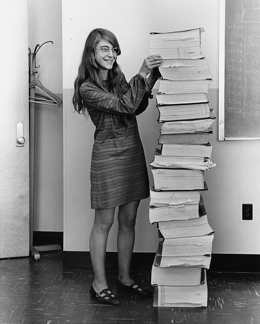 Margaret Hamilton in 1969, standing next to listings of the software she and her MIT team produced for the Apollo project